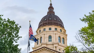 Dome of the Kansas State Capital Building in Topeka with the state flag in the foreground